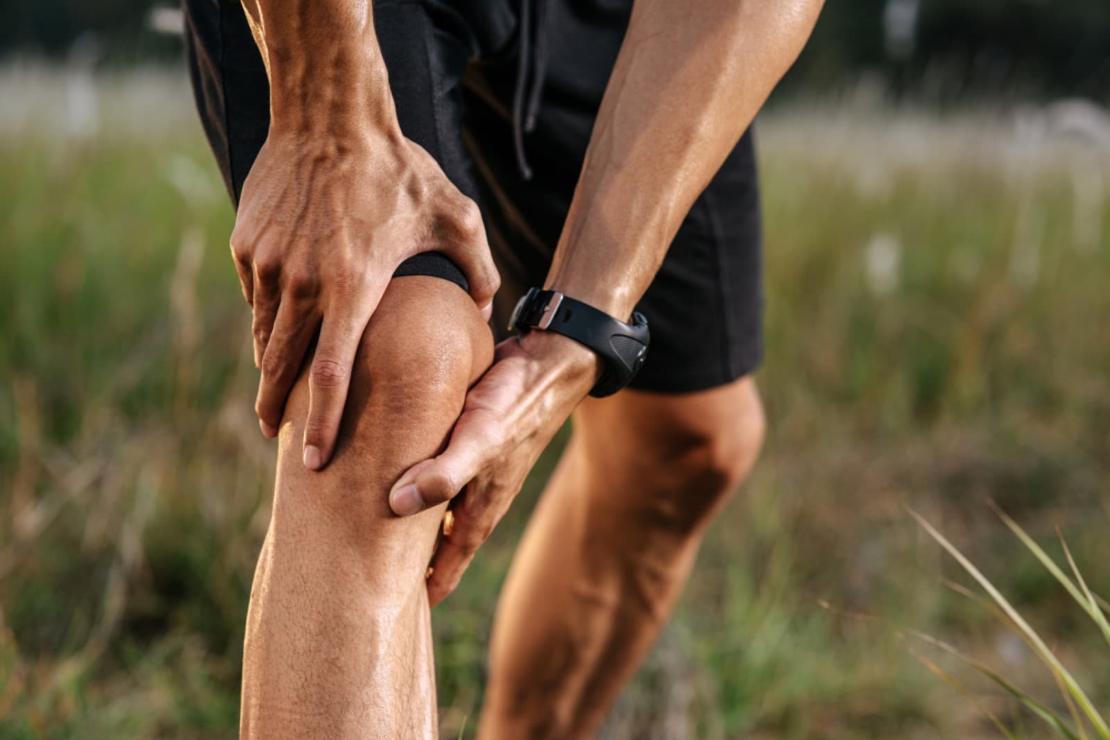 Person holding their knee in pain, causes of knee pain and treatments