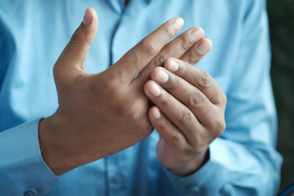 Person massaging aching feet on a bed, living with neuropathy symptoms