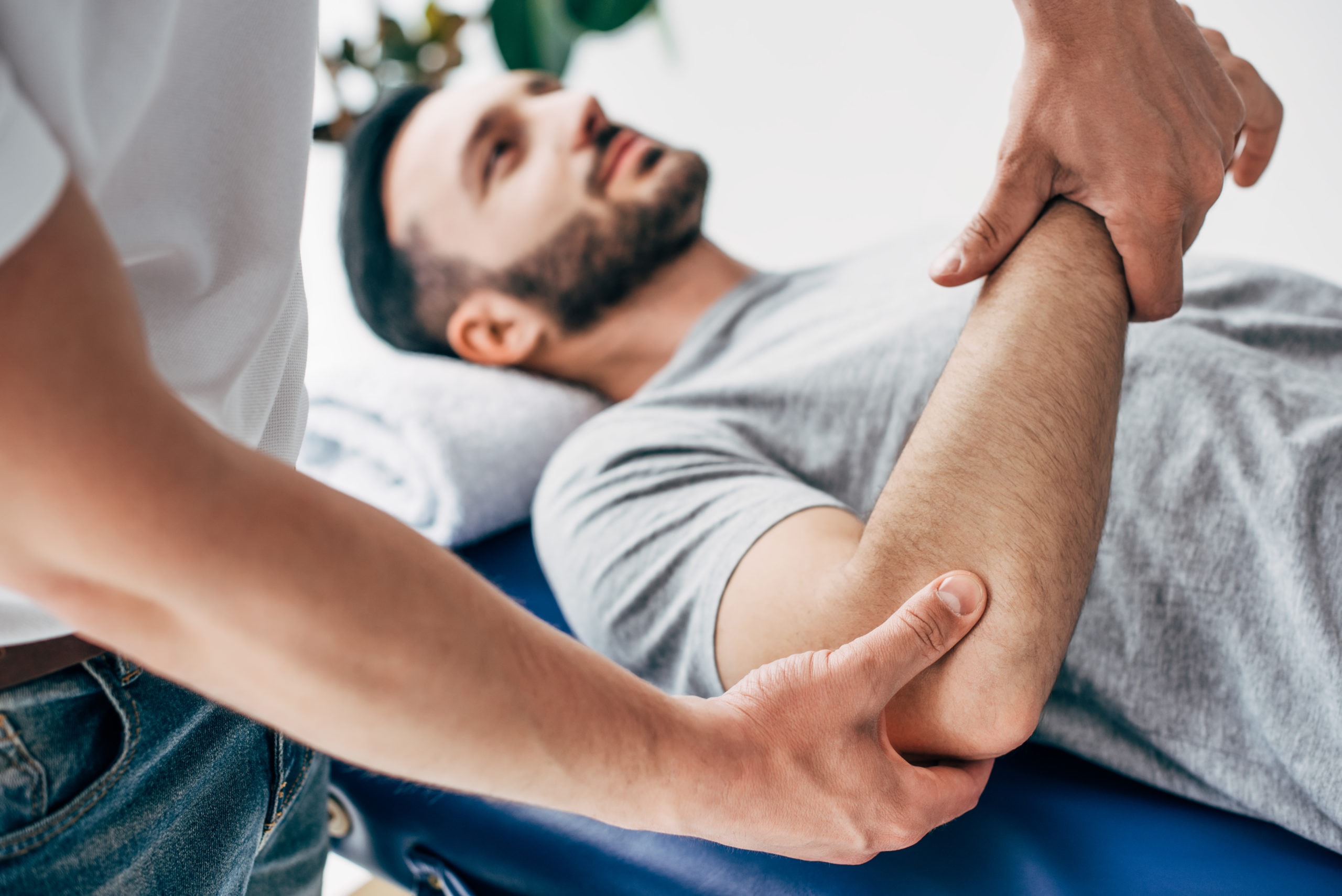 Chiropractor performing a hands-on arm and shoulder adjustment on a patient