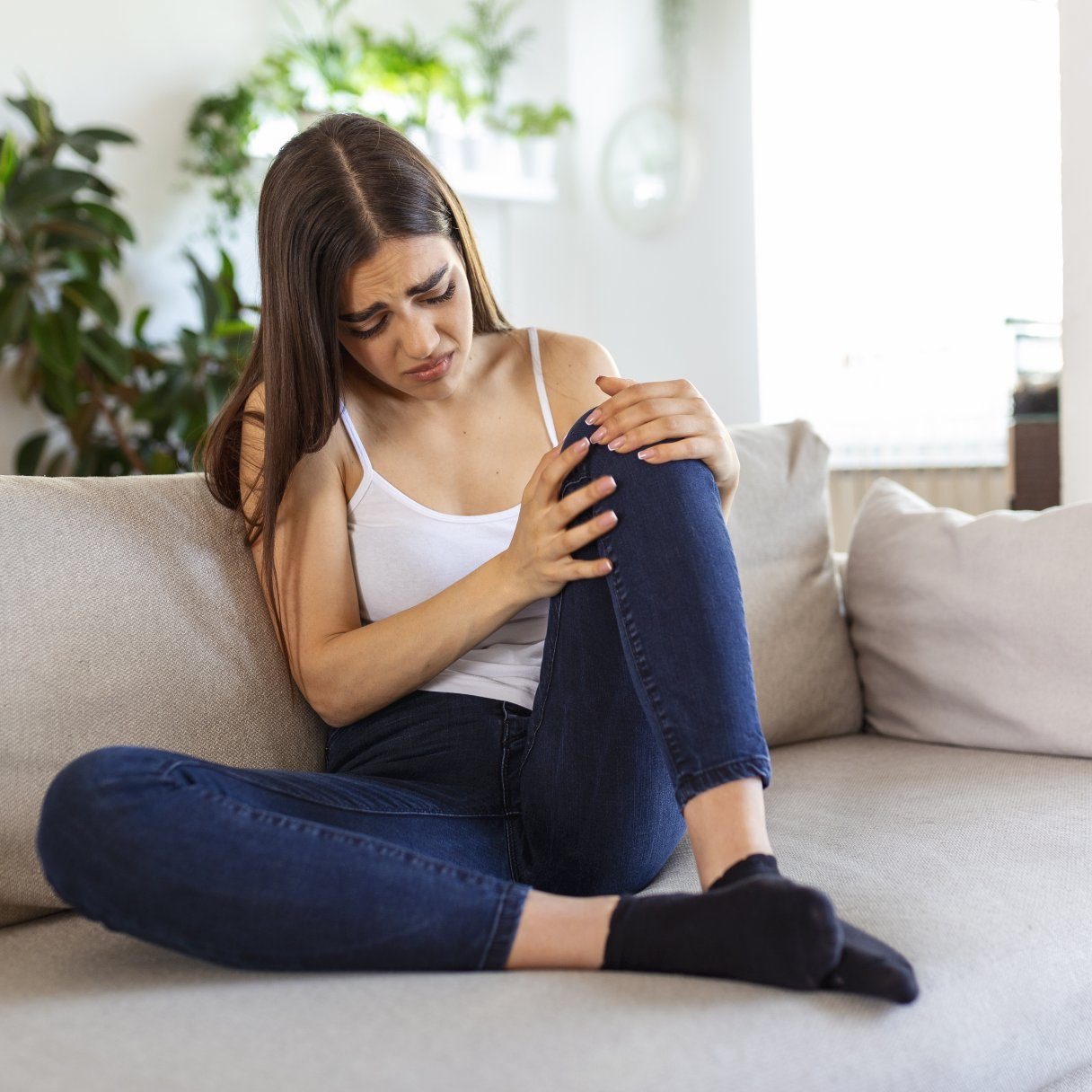 woman holding the knee with pain on sofa,health care and medical concept.